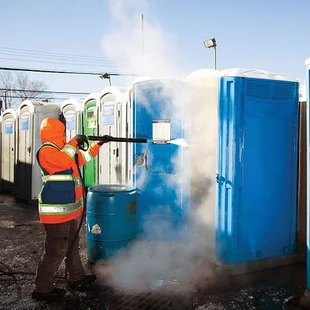 Technician pressure washing portable restroom units